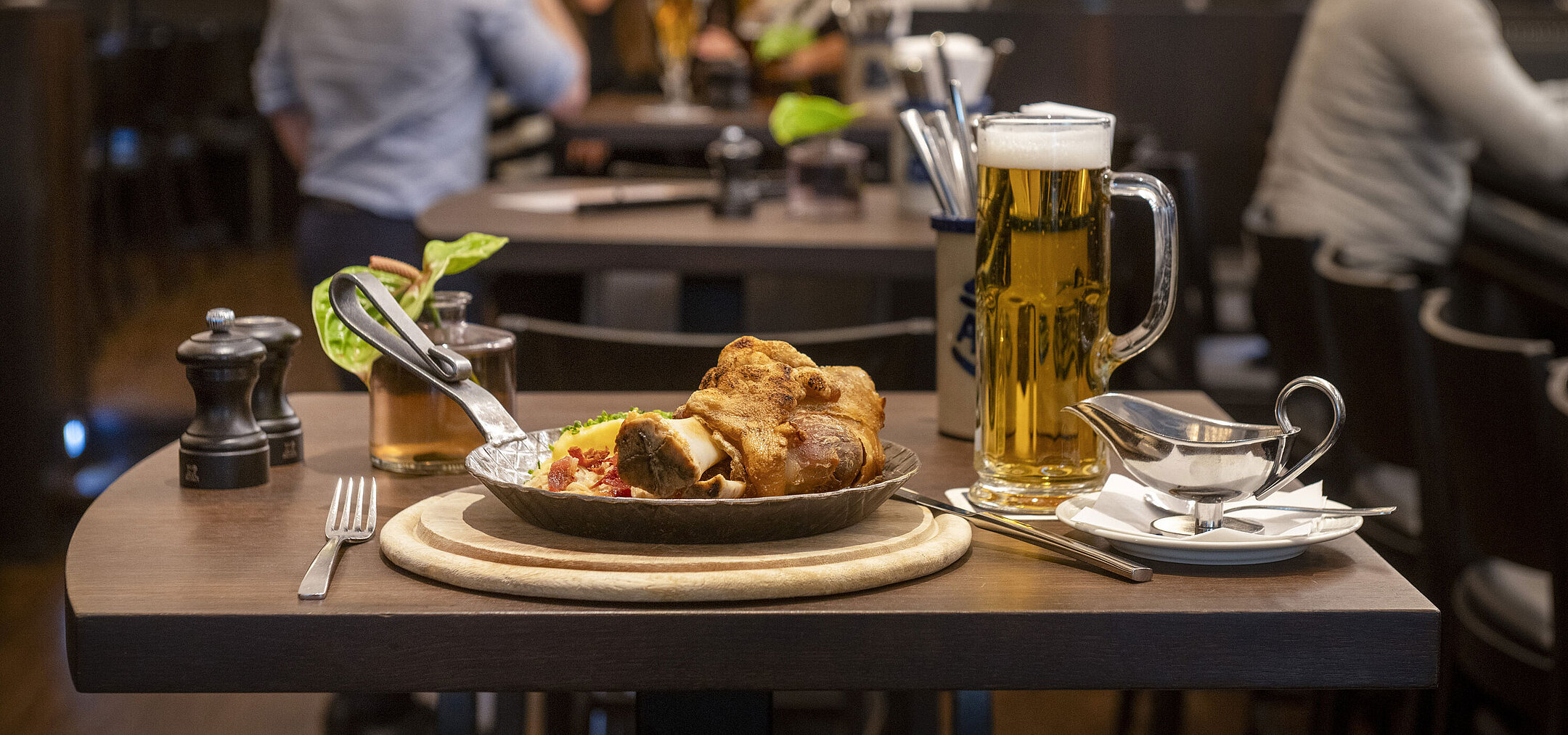 Rheinische Stov Served pork roast with beer at the restaurant of Maritim Düsseldorf, with guests enjoying a cozy atmosphere in the background