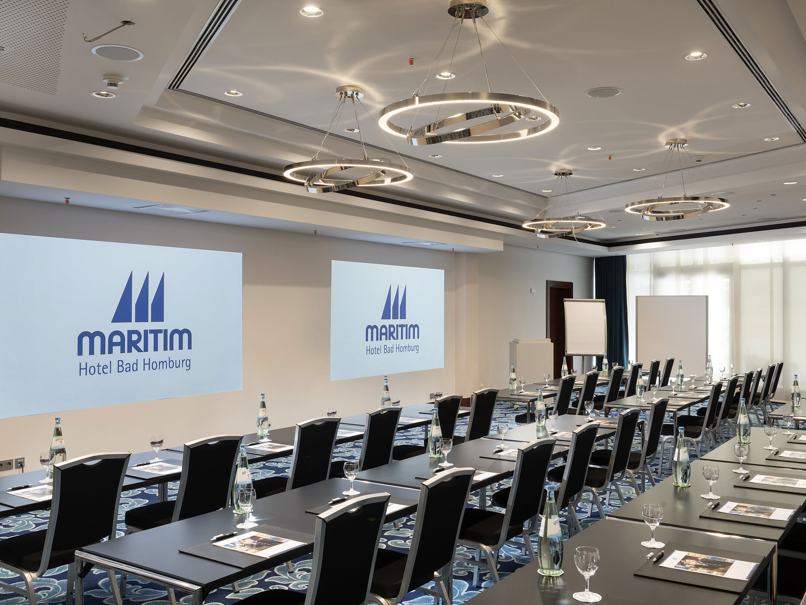 Salle de conférence moderne à l'hôtel Maritim Bad Homburg avec sièges et projection.