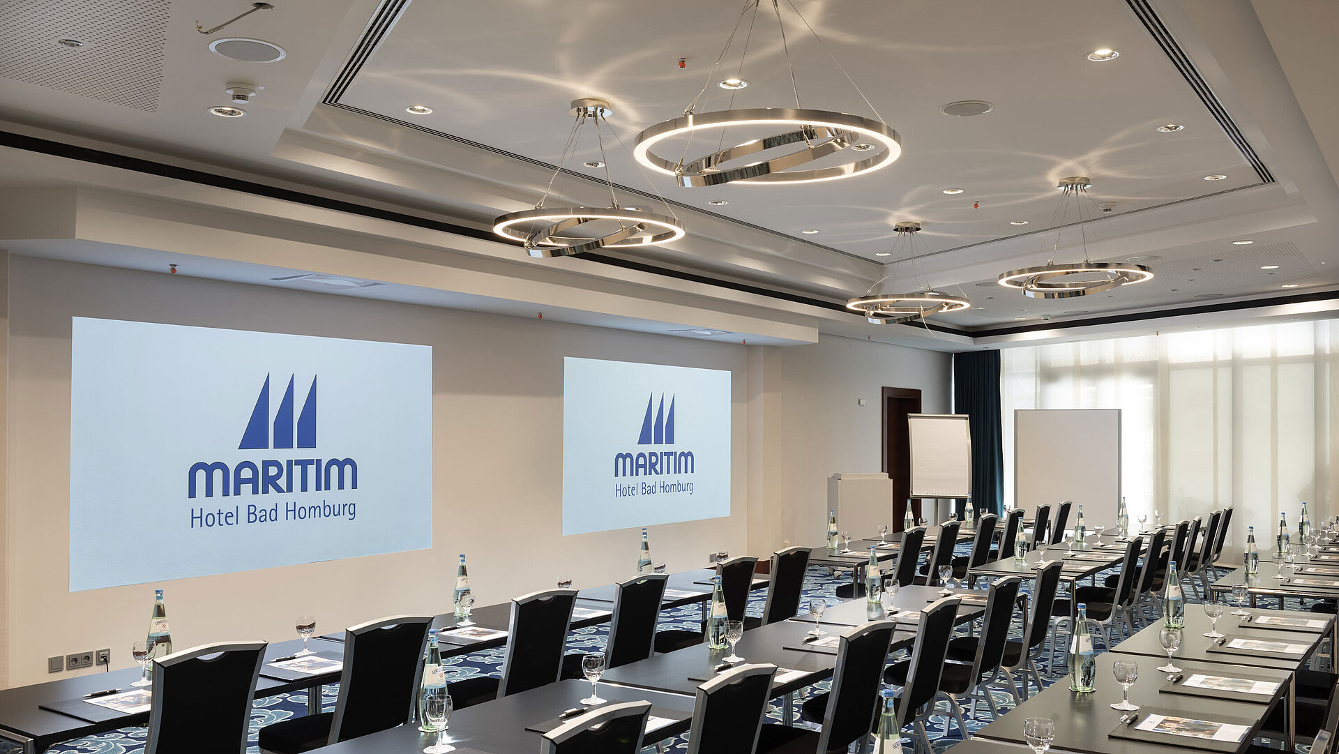 Salle de conférence moderne à l'hôtel Maritim Bad Homburg avec sièges et projection.