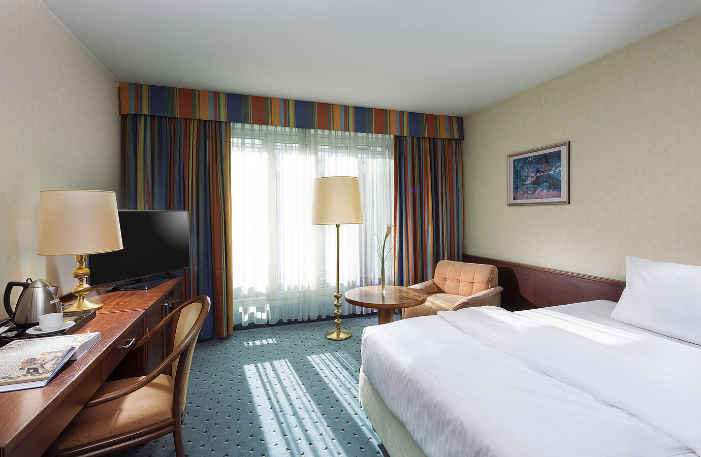 Bright Comfort room at Maritim Hotel Cologne with single bed, desk, TV, armchair, and large windows with curtains.