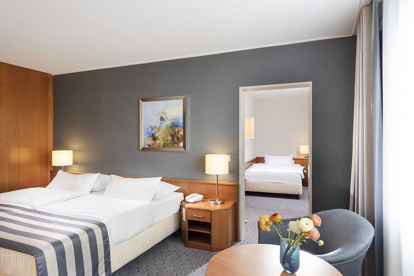 Chambre familiale au Maritim Hotel Ulm avec lit double, coin salon et mur avec miroir élégant