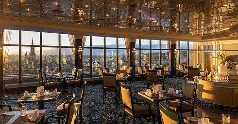 Ristorante nel Maritim Hotel Ulm con eleganti posti a sedere, finestre panoramiche e vista su Ulm al tramonto