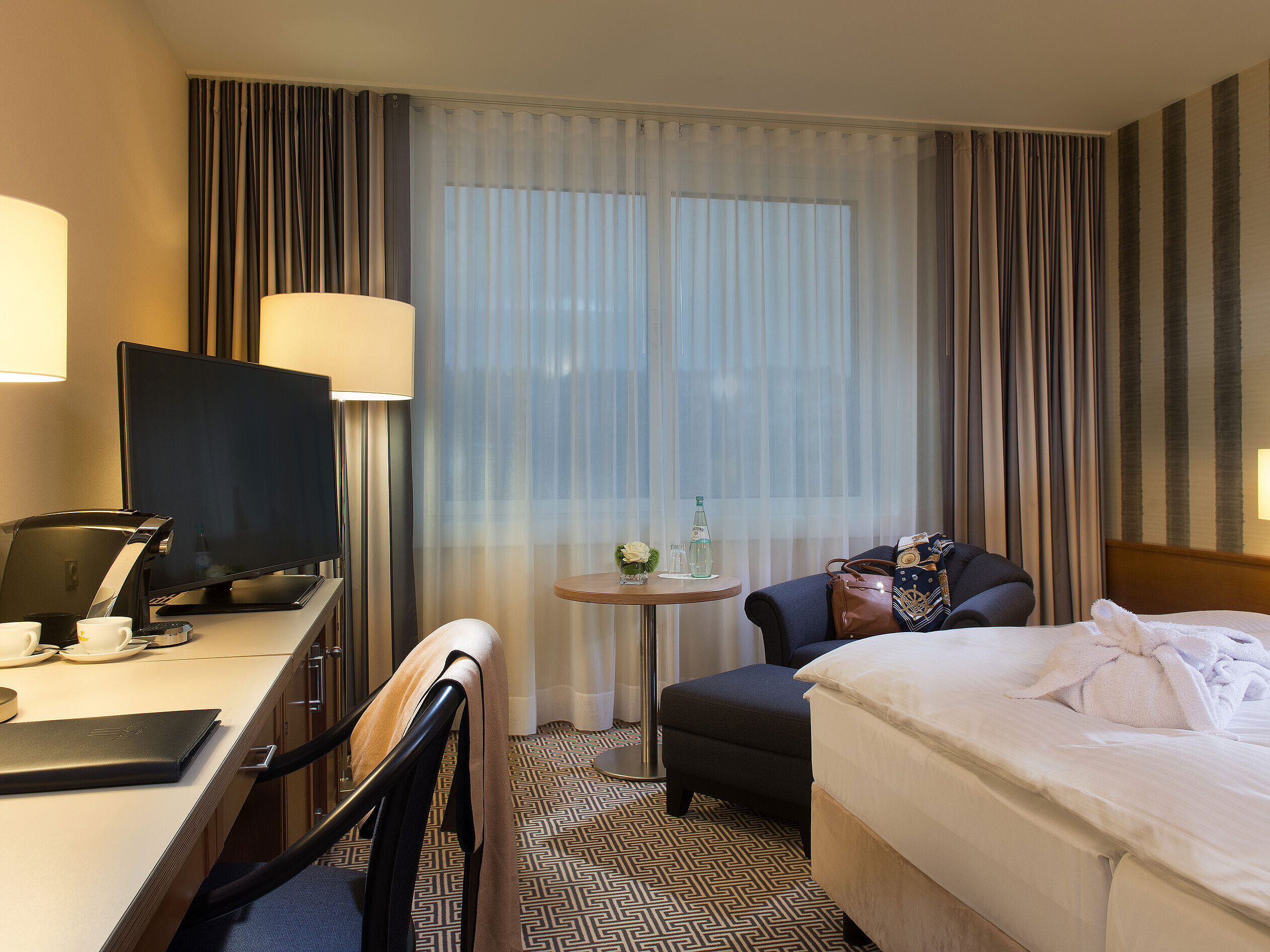 Double room with armchair, desk, coffee machine and daylight at the Maritim Hotel Stuttgart