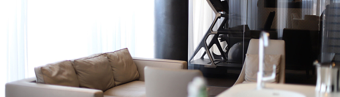 Sofá beige con vista al gimnasio con cinta detrás de cristal en el Maritim Hotel Plaza Tirana