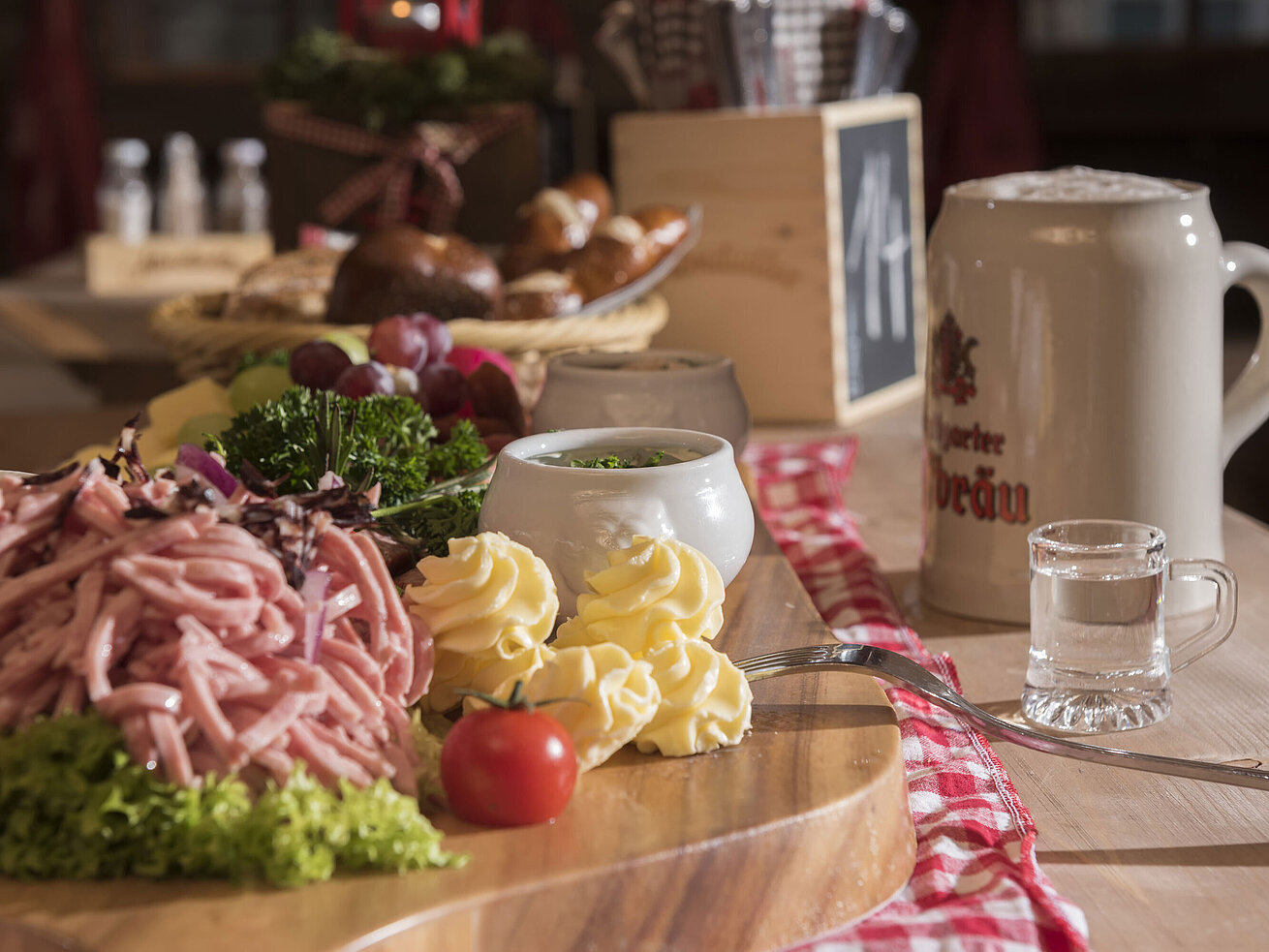 Bayerischer Wurstsalat, Butterrosen, Trauben und Bierkrug auf Holzplatte in der ElbAlm