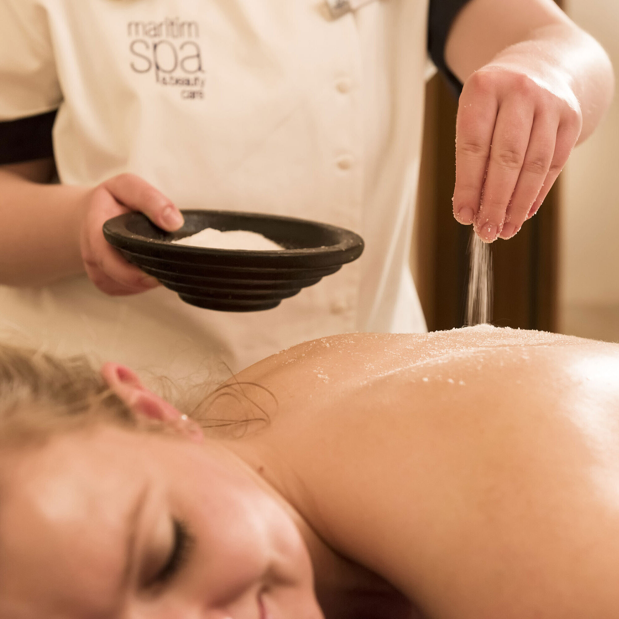 Gros plan d’un traitement au sel sur le dos au spa du Maritim Seehotel Timmendorfer Strand.