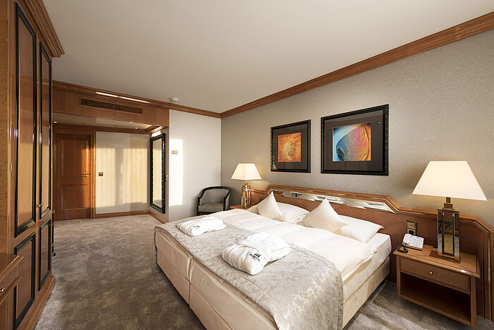 Chambre confortable au Maritim Hotel Ulm avec lit double, détails en bois et peignoirs