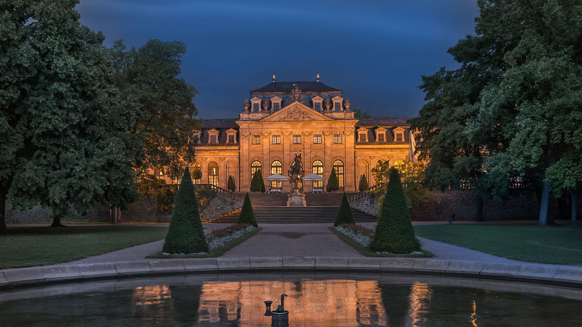The Maritim Hotel Fulda, beautifully illuminated at night, reflecting in the water basin of the Baroque garden.
