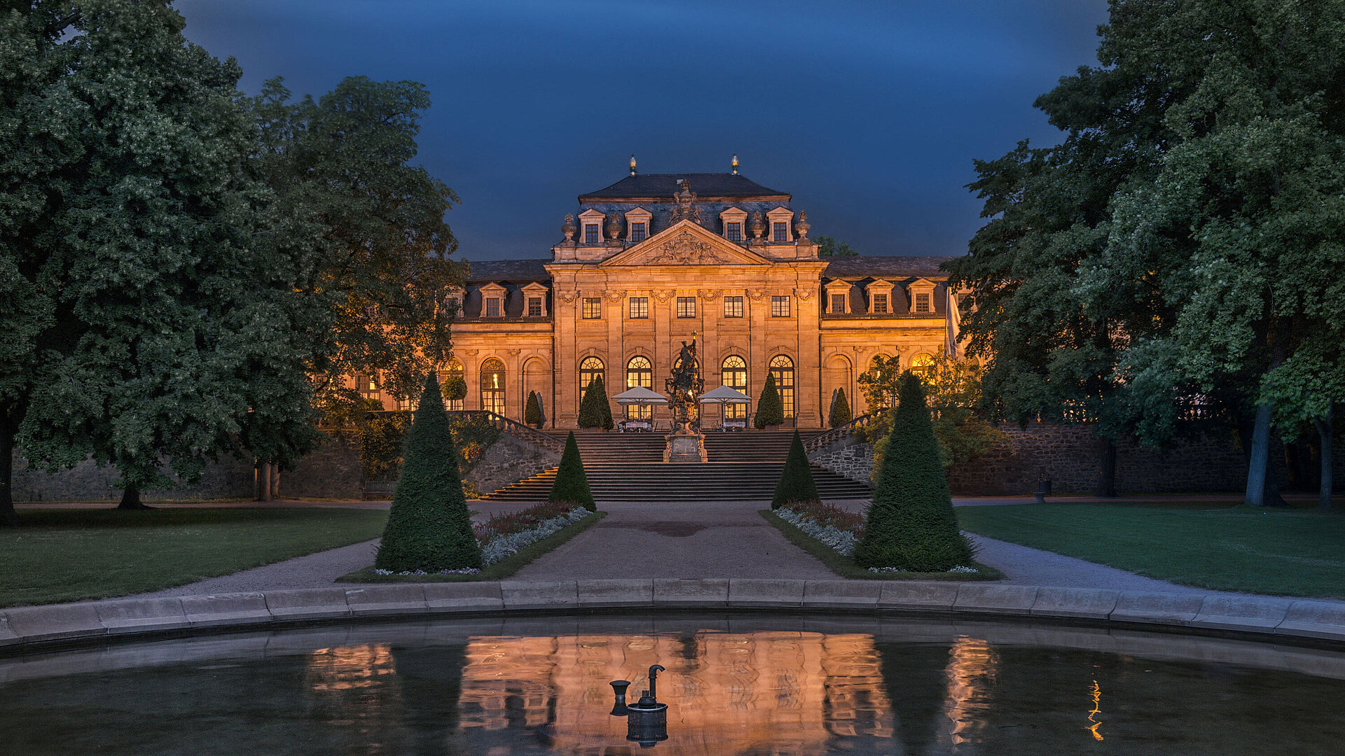 The Maritim Hotel Fulda, beautifully illuminated at night, reflecting in the water basin of the Baroque garden.