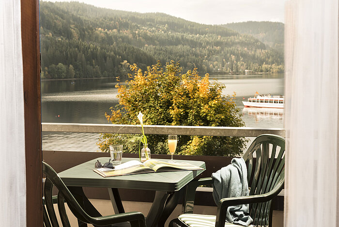Balcone con tavolo, bevanda e vista sul lago Titisee e natura