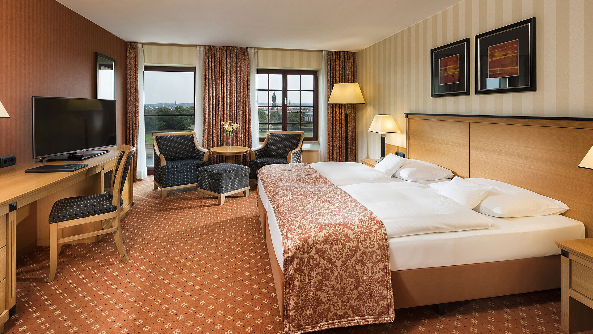 Chambre supérieure à l'hôtel Maritim de Dresde avec lit double élégant, bureau et coin salon avec vue sur la ville.