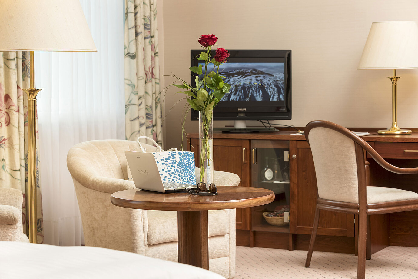 Cosy seating area with roses, laptop and TV in the room of Maritim Hotel Bad Wildungen