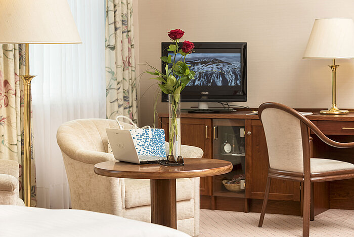 Cosy seating area with roses, laptop and TV in the room of Maritim Hotel Bad Wildungen