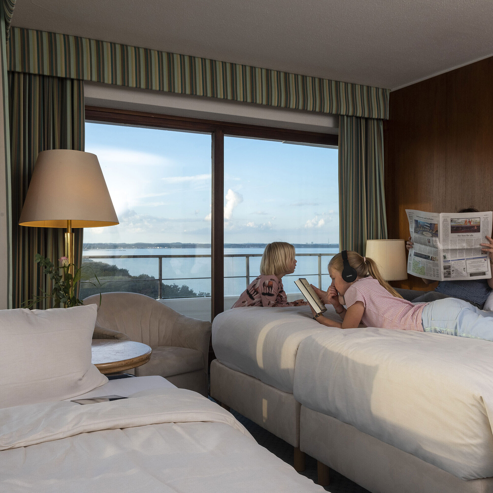 Habitación familiar lado del parque Habitación familiar con niños leyendo, usando una tableta y disfrutando de las vistas al mar.