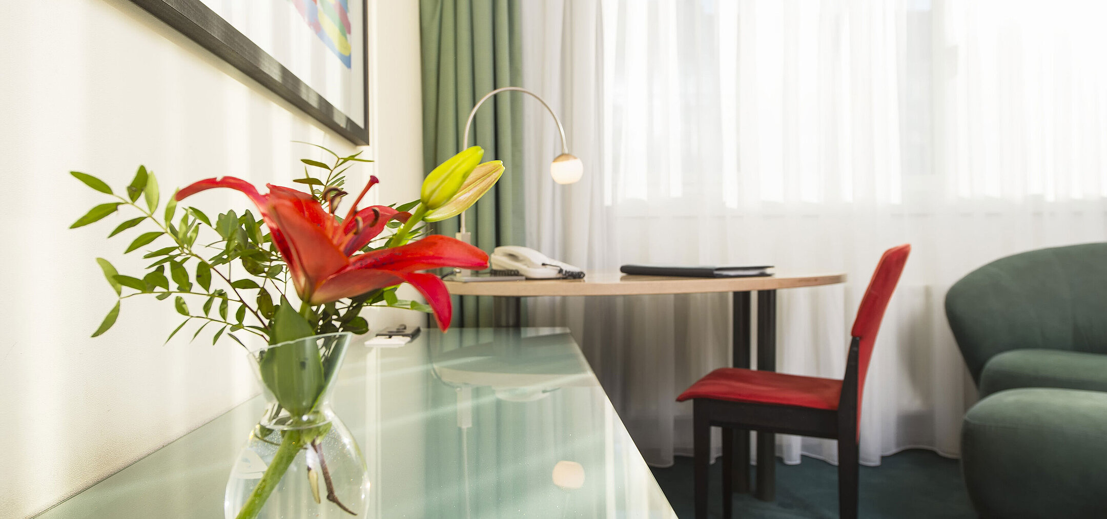 Camera Classic elegante al Maritim proArte Hotel Berlino, con un fiore rosso in vaso, scrivania e area salotto.