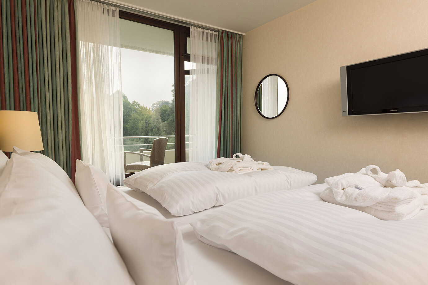 Letto matrimoniale con TV, accappatoio e vista balcone al Maritim Hotel Bad Salzuflen