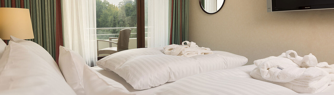 Cama doble con TV, albornoz y vista al balcón en el Maritim Hotel Bad Salzuflen