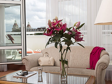 Bright living room with flowers, sofa and balcony view of towers at Maritim Hotel Bad Wildungen