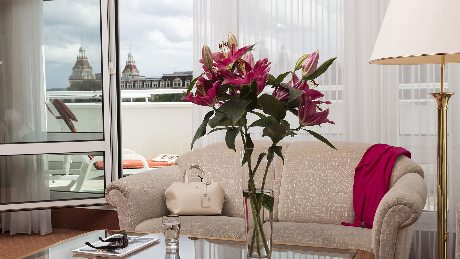 Bright living room with flowers, sofa and balcony view of towers at Maritim Hotel Bad Wildungen