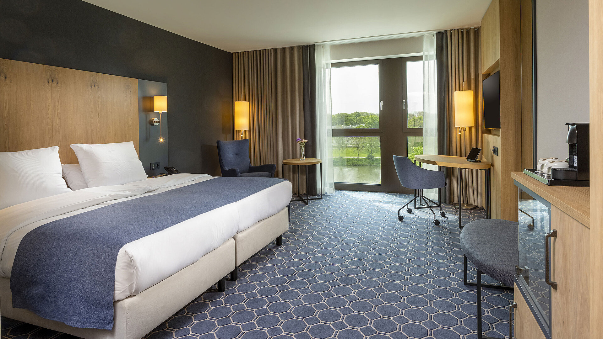 Spacious double room at Maritim Hotel Ingolstadt with large bed, desk, and a view of the river.