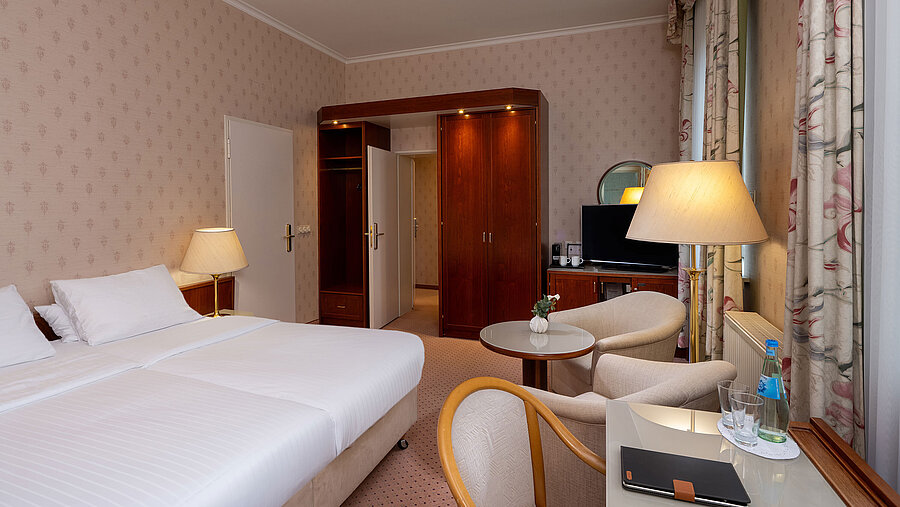 Habitación familiar Comfort con cama doble, zona de estar, escritorio, TV y decoración luminosa y acogedora.