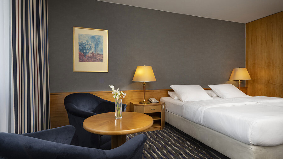 Camera d'hotel con letto matrimoniale, area salotto e arredamento elegante, ideale per rilassarsi