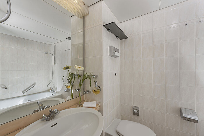 Bagno luminoso al Maritim Hotel Bad Salzuflen con doccia, grande specchio e piastrelle bianche