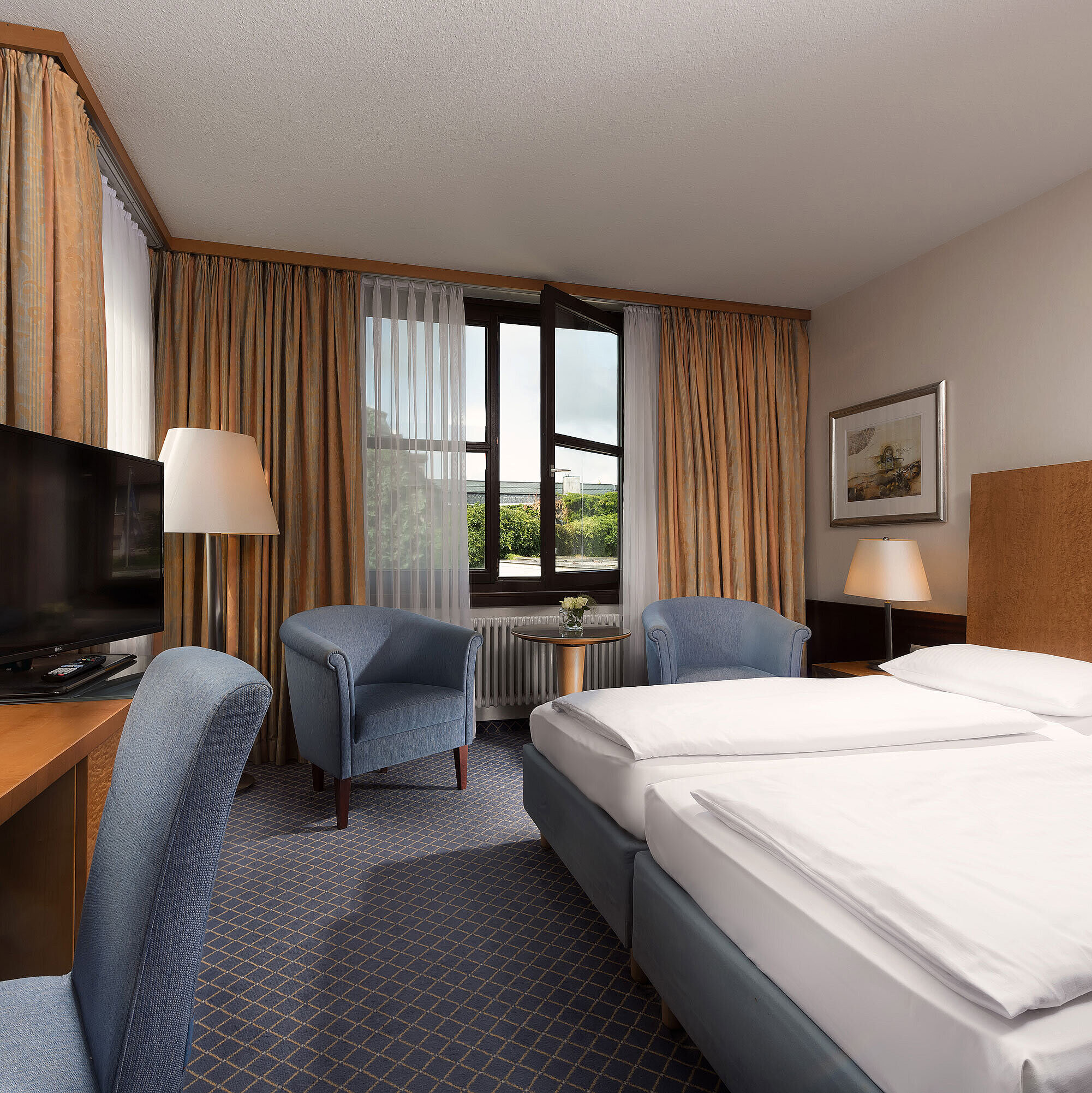 Camera Classic al Maritim Hotel Fulda con letto doppio, scrivania, angolo salotto e ampia finestra.