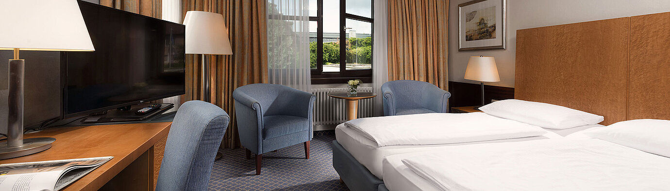 Classic room at Maritim Hotel Fulda with a cozy double bed, desk, seating area, and large window.