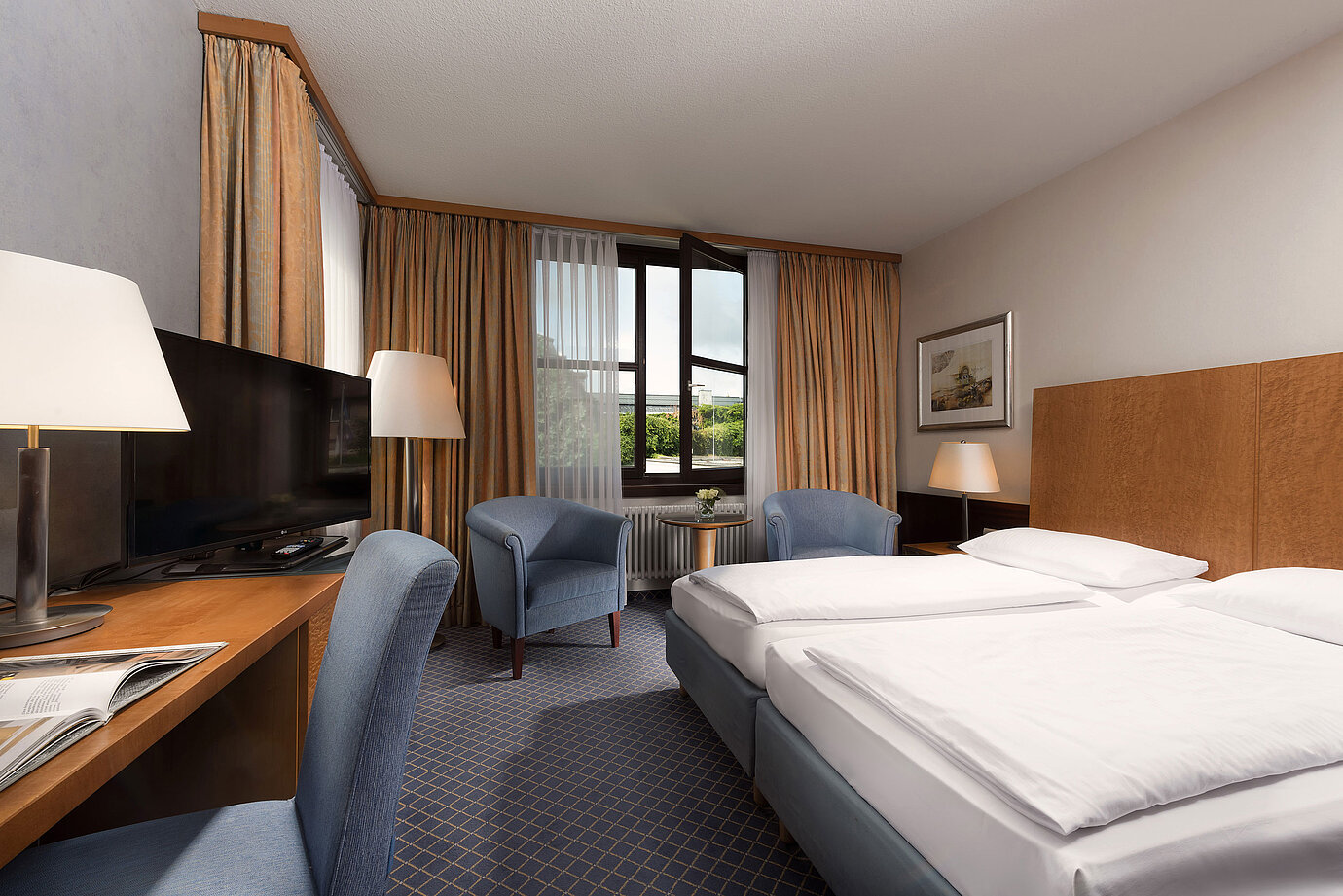 Camera Classic al Maritim Hotel Fulda con letto doppio, scrivania, angolo salotto e ampia finestra.