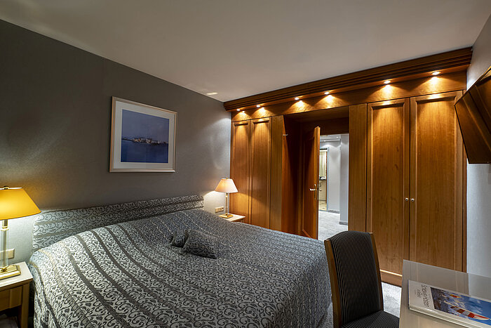 Chambre de la Grand Suite de l'hôtel Maritim Kiel avec design élégant, grand lit et éclairage raffiné.
