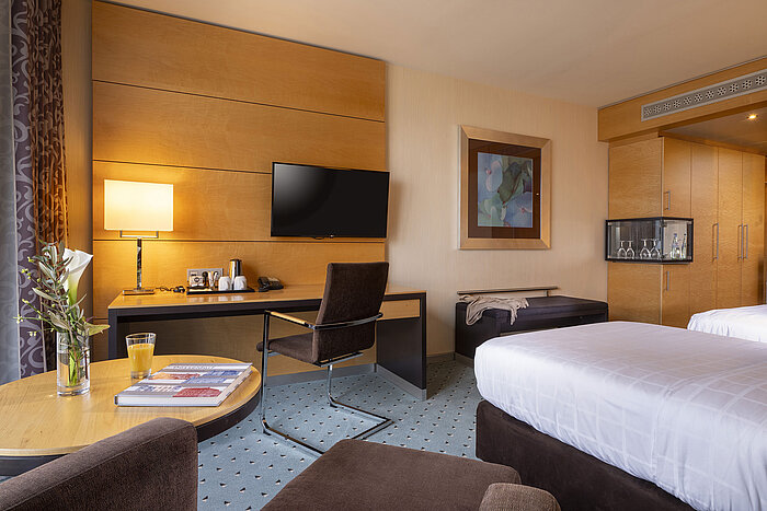 Habitación clásica en el Maritim Hotel Düsseldorf con escritorio, televisor de pantalla plana, cama doble y decoración elegante.