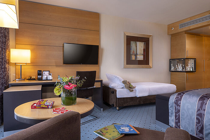 Habitación familiar superior en el Maritim Hotel Düsseldorf con cama adicional, escritorio y ambiente acogedor.