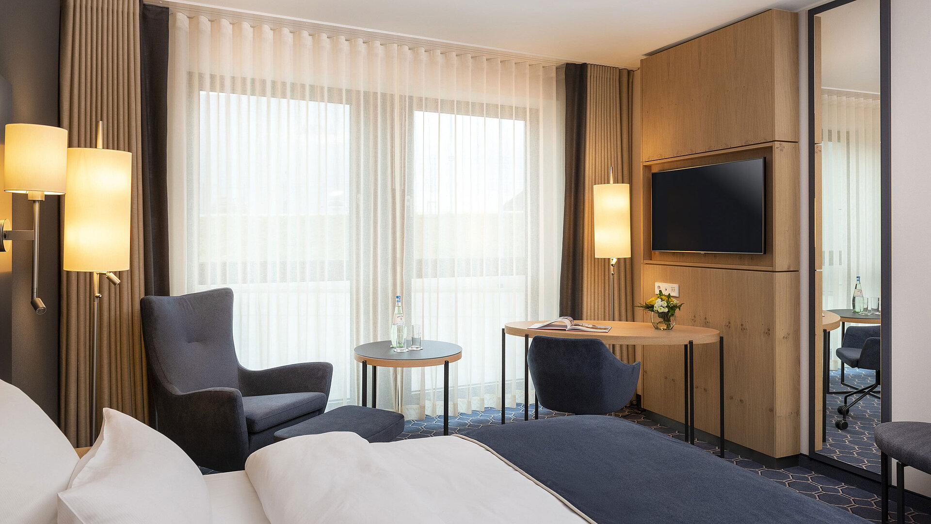 Bright room with a desk, TV, and cozy seating area at Maritim Hotel Ingolstadt. Ideal for business trips.