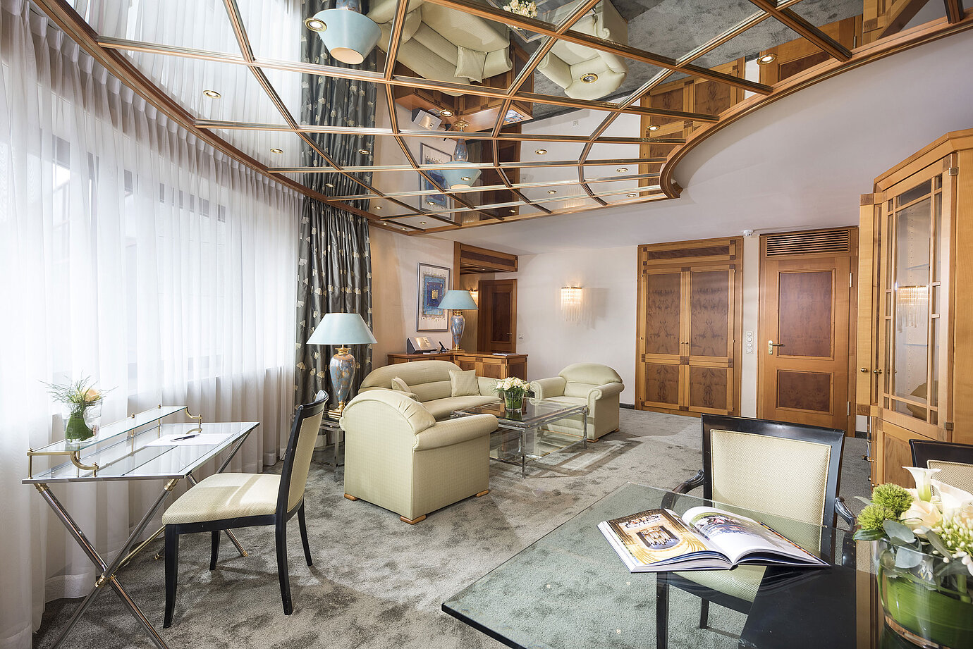 Spacious suite with elegant furnishings, glass table and cosy lounge at Maritim Hotel Magdeburg