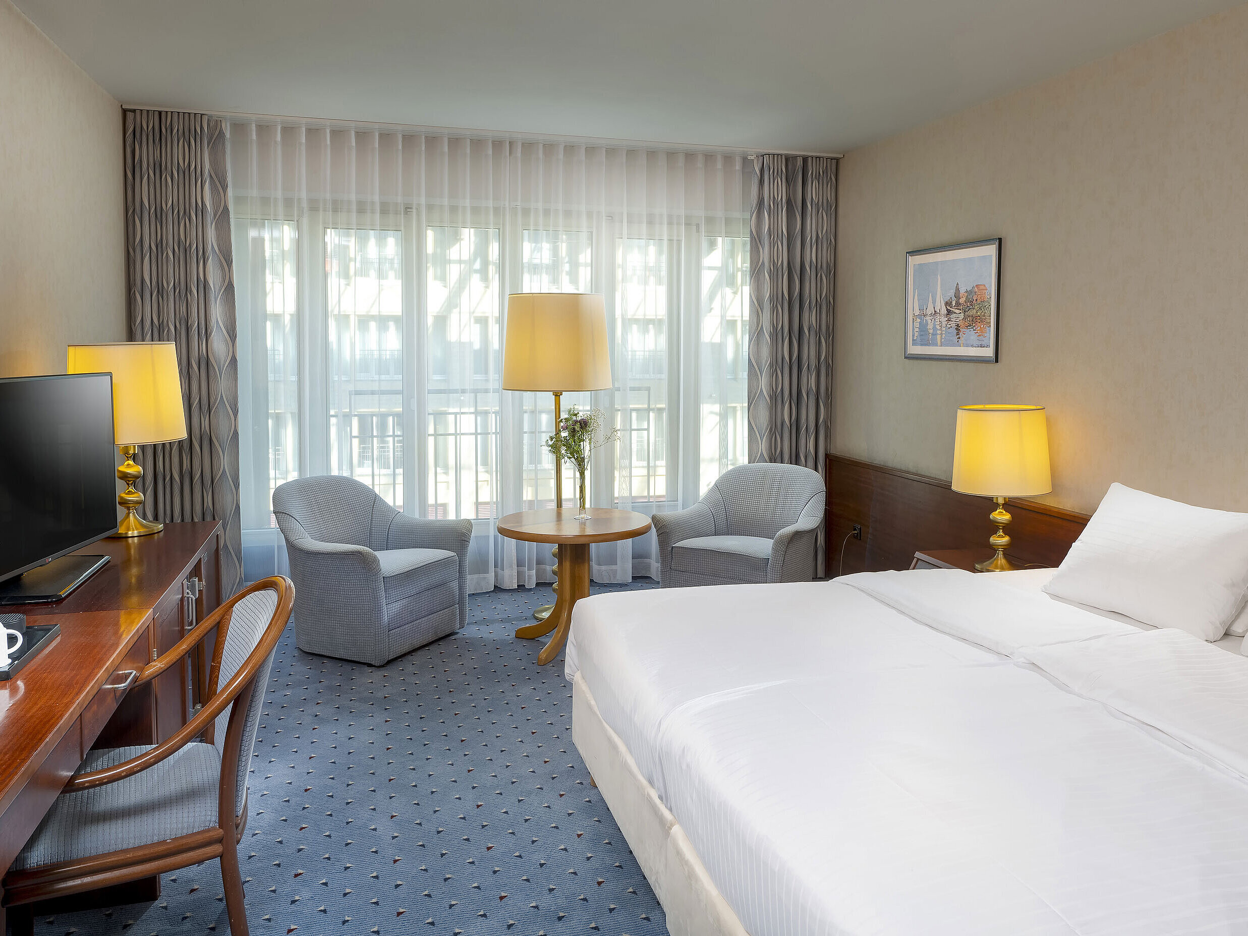 Classic room at the Maritim Hotel Cologne with a double bed, cozy seating area, desk, and TV.