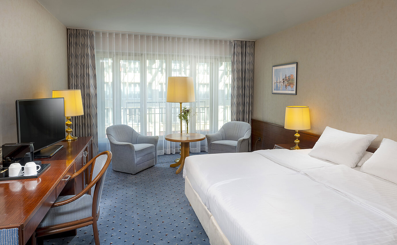 Classic room at the Maritim Hotel Cologne with a double bed, cozy seating area, desk, and TV.