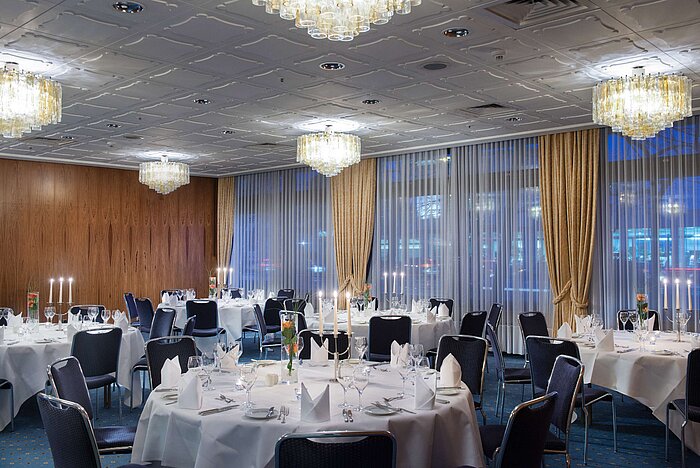 Elegante sala de eventos en el Hotel Maritim Darmstadt con mesas redondas, velas y un ambiente sofisticado.