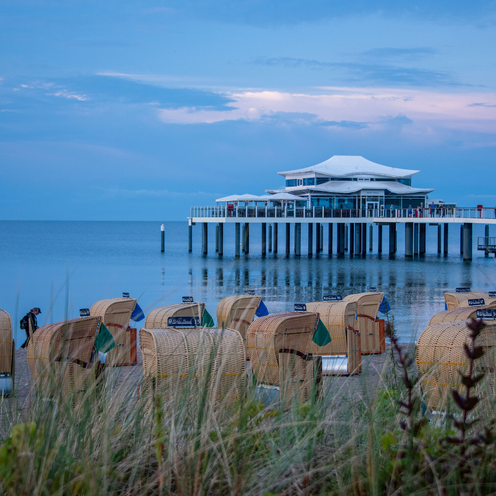 Beach chairs and pier at sunset Beach chairs on the sandy shore with a view of the Baltic Sea and a pier at sunset.