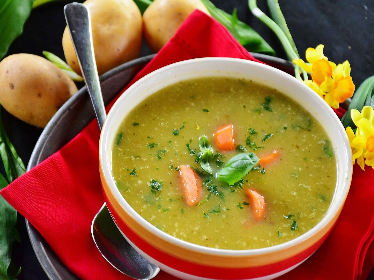 Creamy vegetable soup with carrot pieces and fresh herbs served in a bowl.