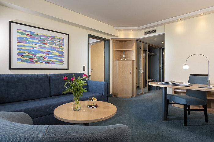 Modern suite with sofa, desk, and stylish artwork at the Maritim proArte Hotel Berlin.