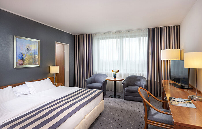 Chambre familiale au Maritim Hotel Ulm avec lit double, bureau, coin salon et lumière naturelle