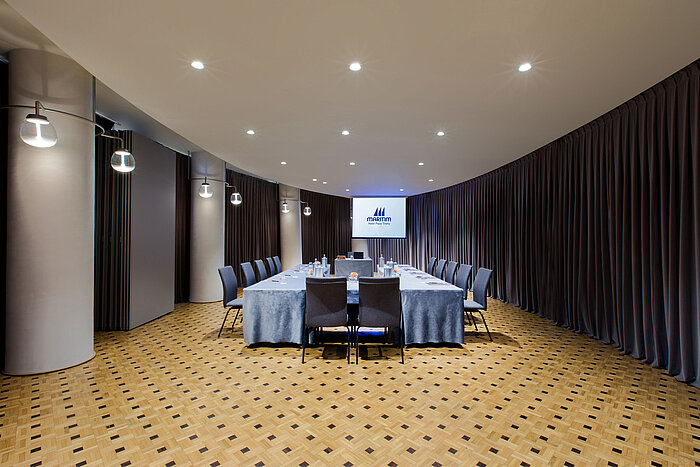 Sala de reuniones moderna en Maritim Hotel Plaza Tirana con disposición en U, pantalla y cortinas elegantes