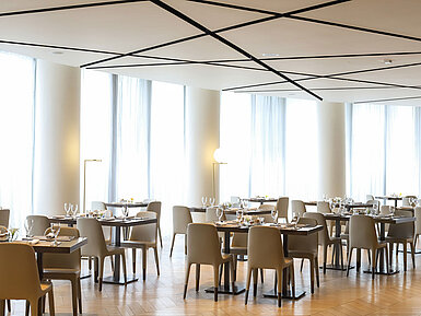 Spacious, light-filled restaurant area with modern ceiling at Maritim Hotel Plaza Tirana