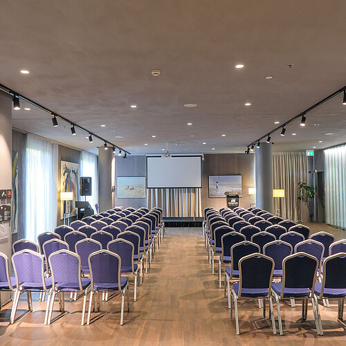 Sala luminosa en Maritim Hotel Plaza Tirana con butacas en filas y pantalla