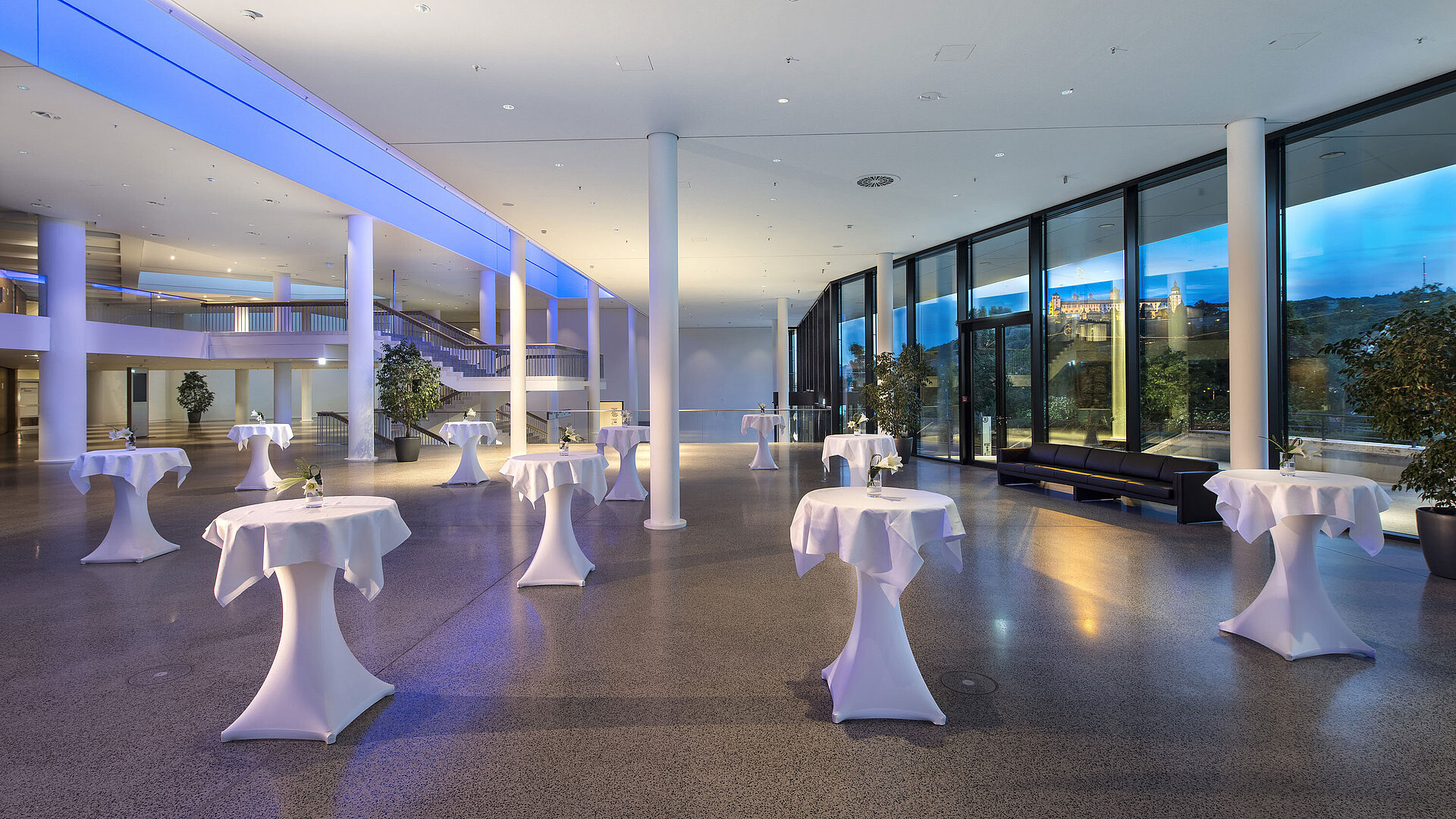 Vestíbulo moderno del Maritim Hotel Würzburg con mesas altas y vista a la fortaleza