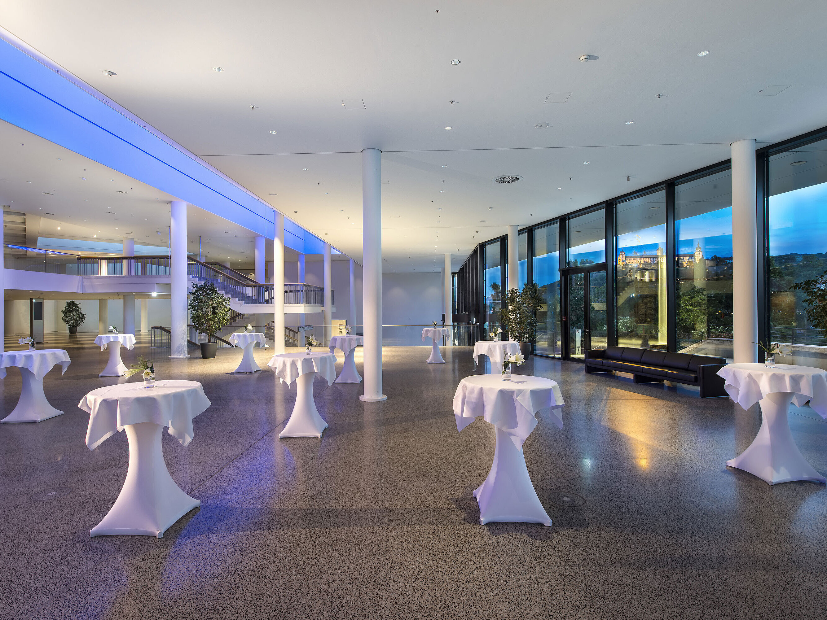 Vestíbulo moderno del Maritim Hotel Würzburg con mesas altas y vista a la fortaleza