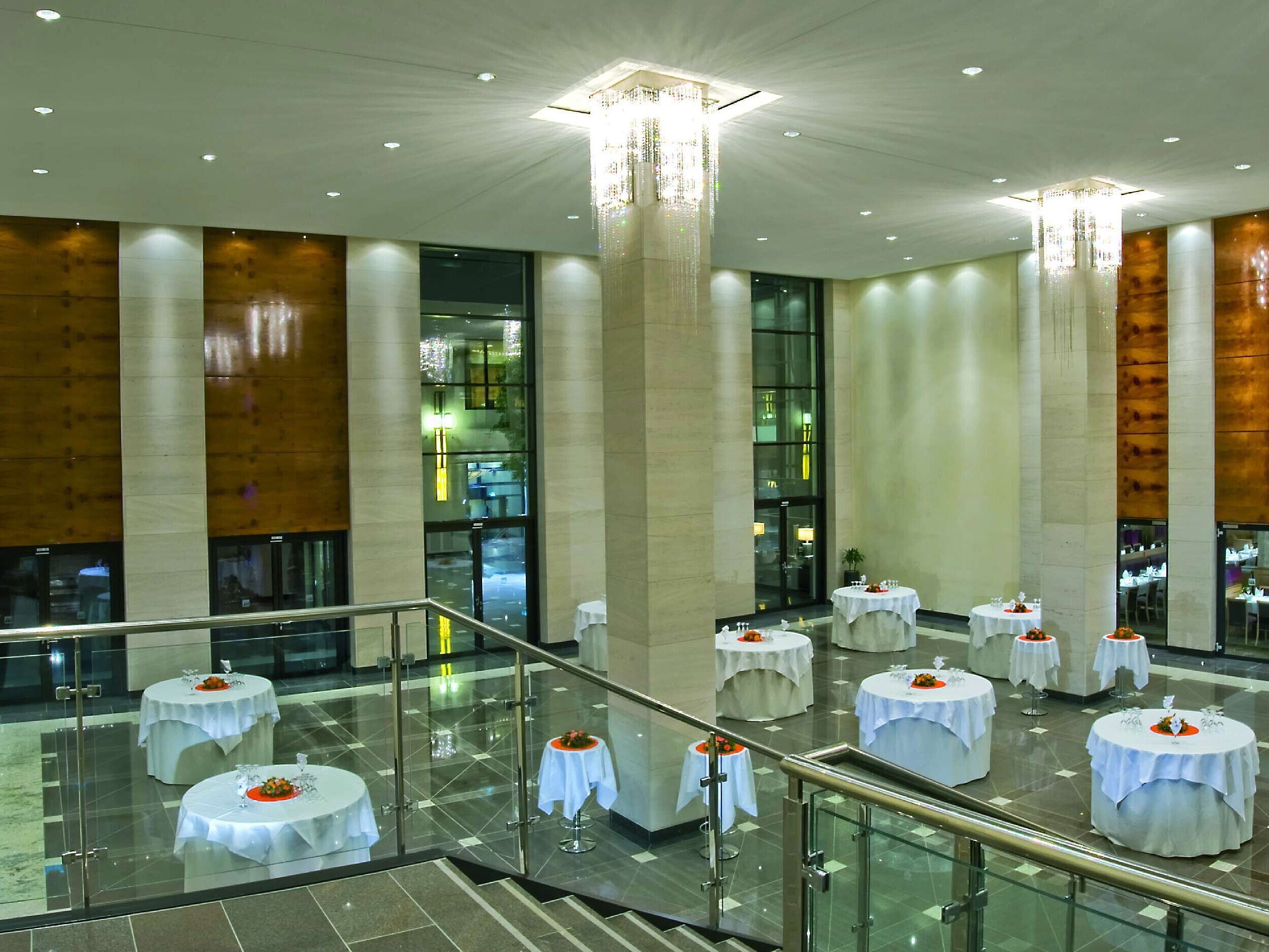 Elegante vestíbulo del salón en el Maritim Hotel Düsseldorf con techos altos,mesas decoradas con estilo e iluminación moderna