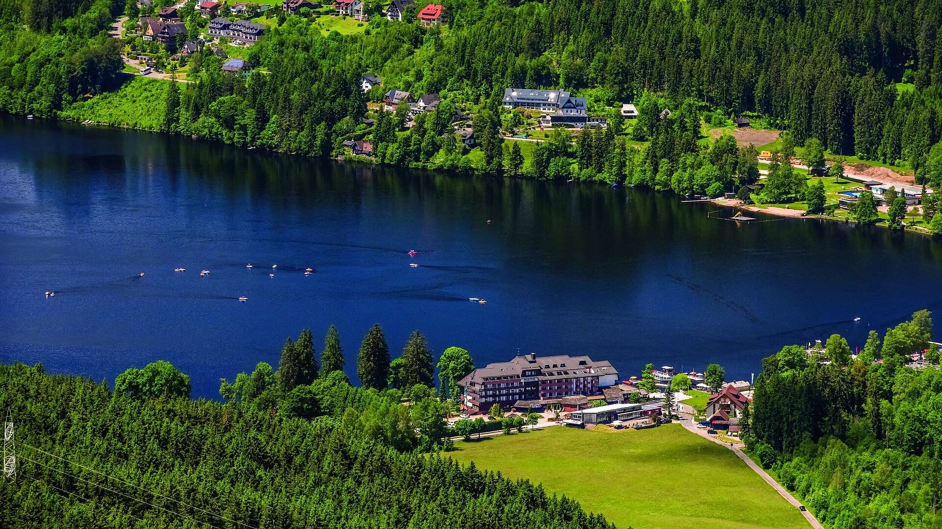 Aerial view of the Maritim Hotel on Lake Titisee with surrounding forest and pedal boats on the water