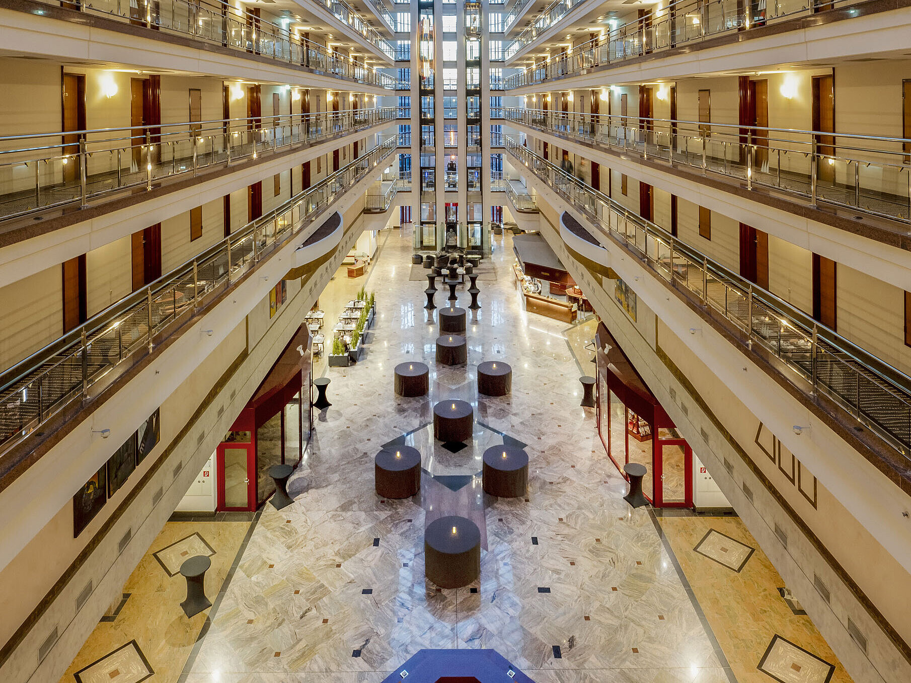 Impressionante hall dell'hotel con soffitto di vetro, più piani e aree salotto, che crea un ambiente spazioso ed elegante